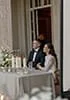 A couple at a wedding reception sitting at a table with candles and flowers.