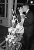 A black and white image of a couple in formal attire sharing a kiss while holding champagne glasses next to a tower of filled glasses.
