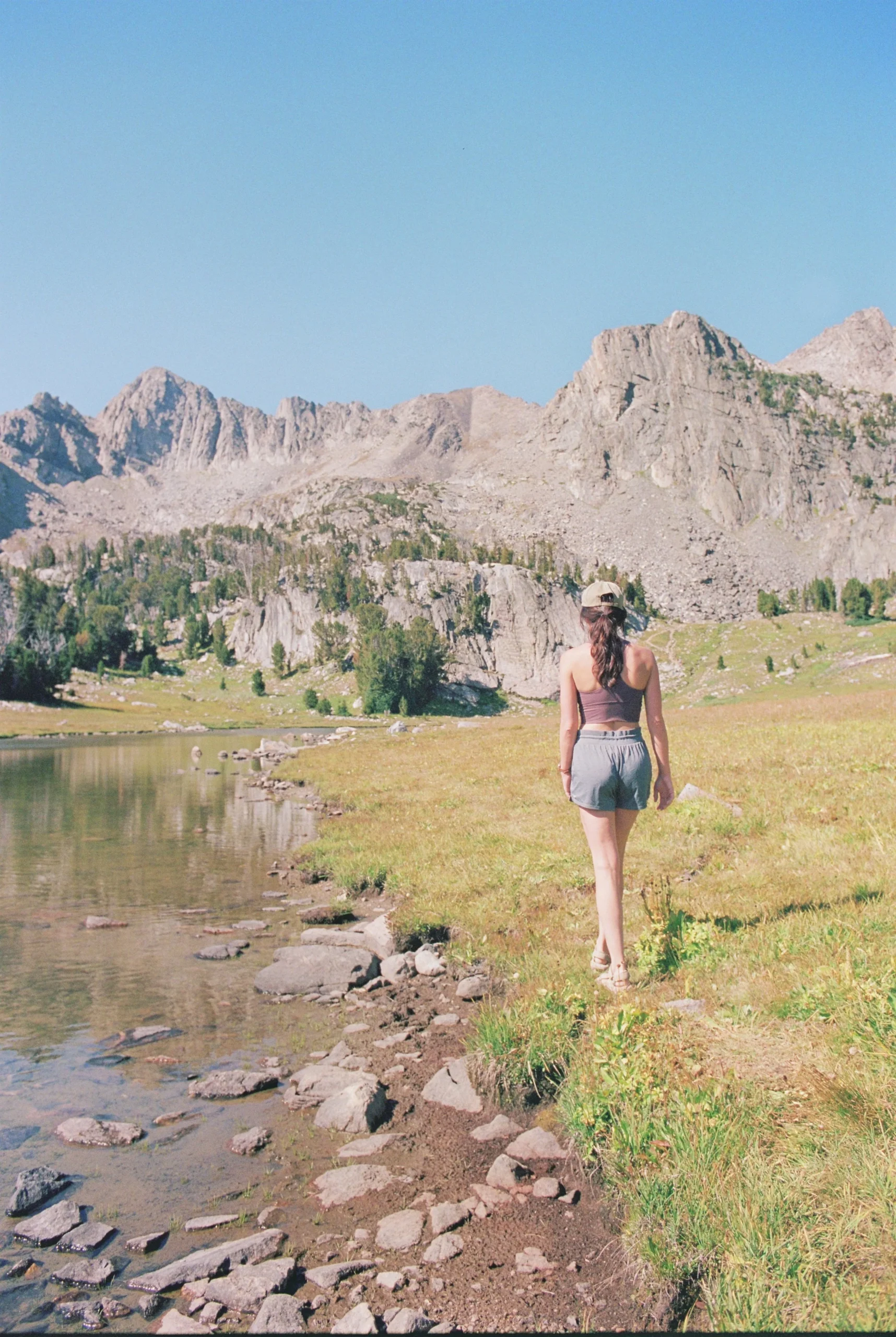 Woman walking along a lakeside path with mountains in the background