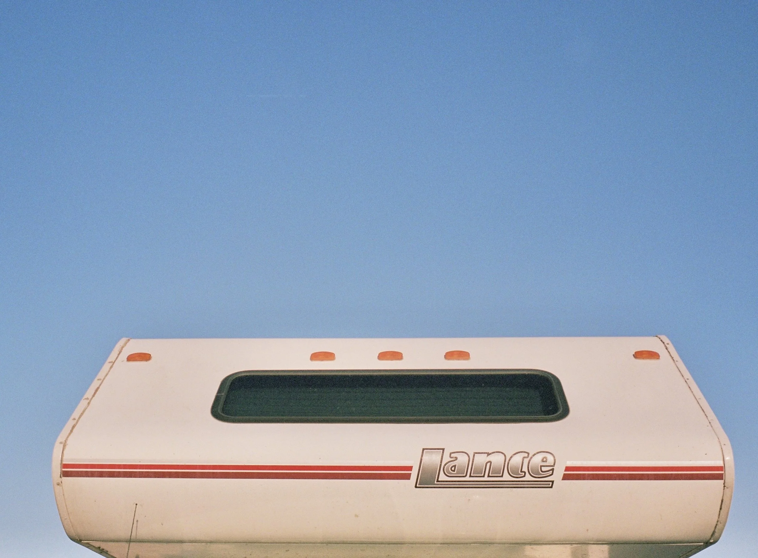 Roof of a Lance camper against a clear blue sky.