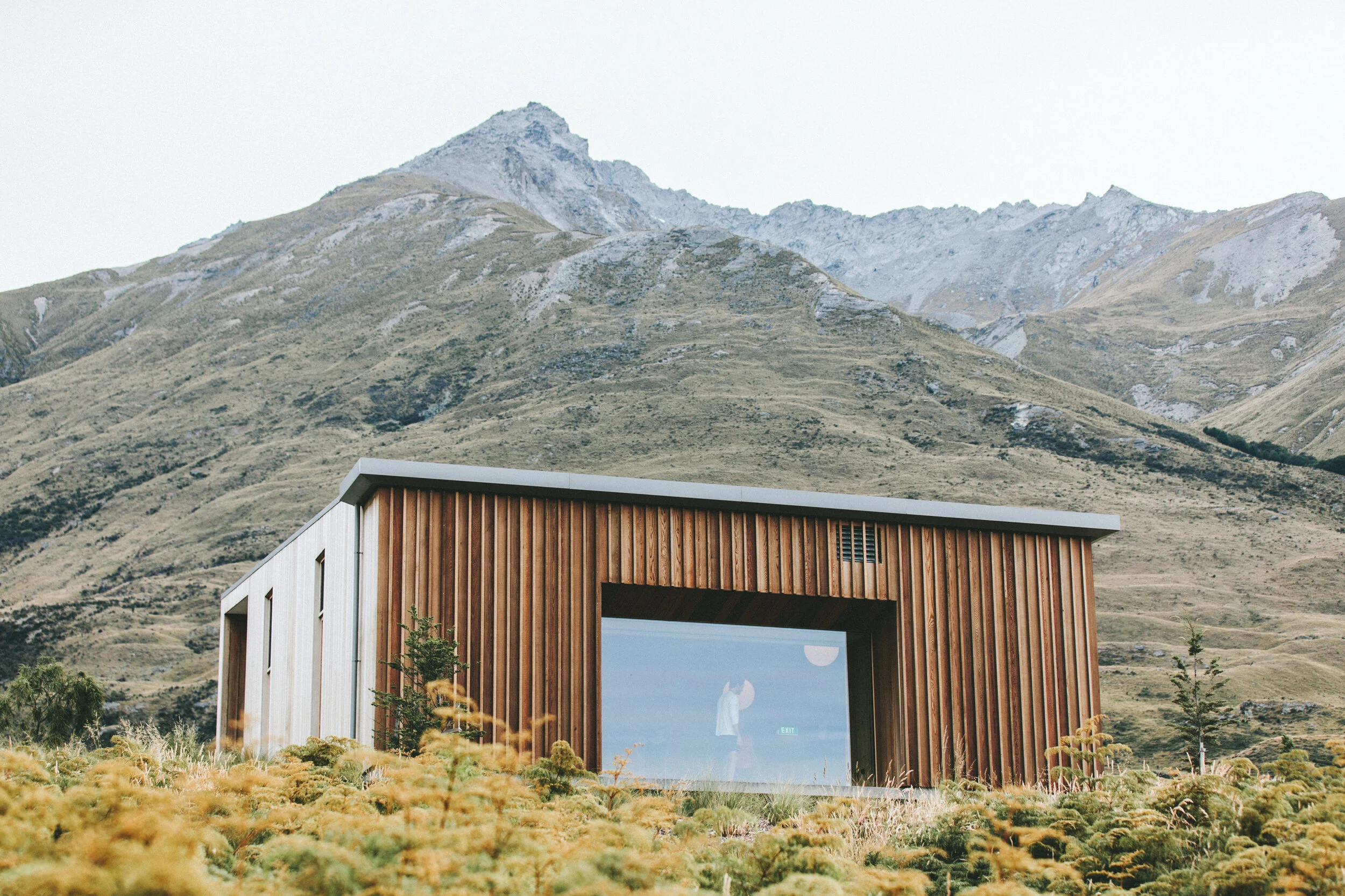 Modern wooden cabin with large window in mountainous landscape