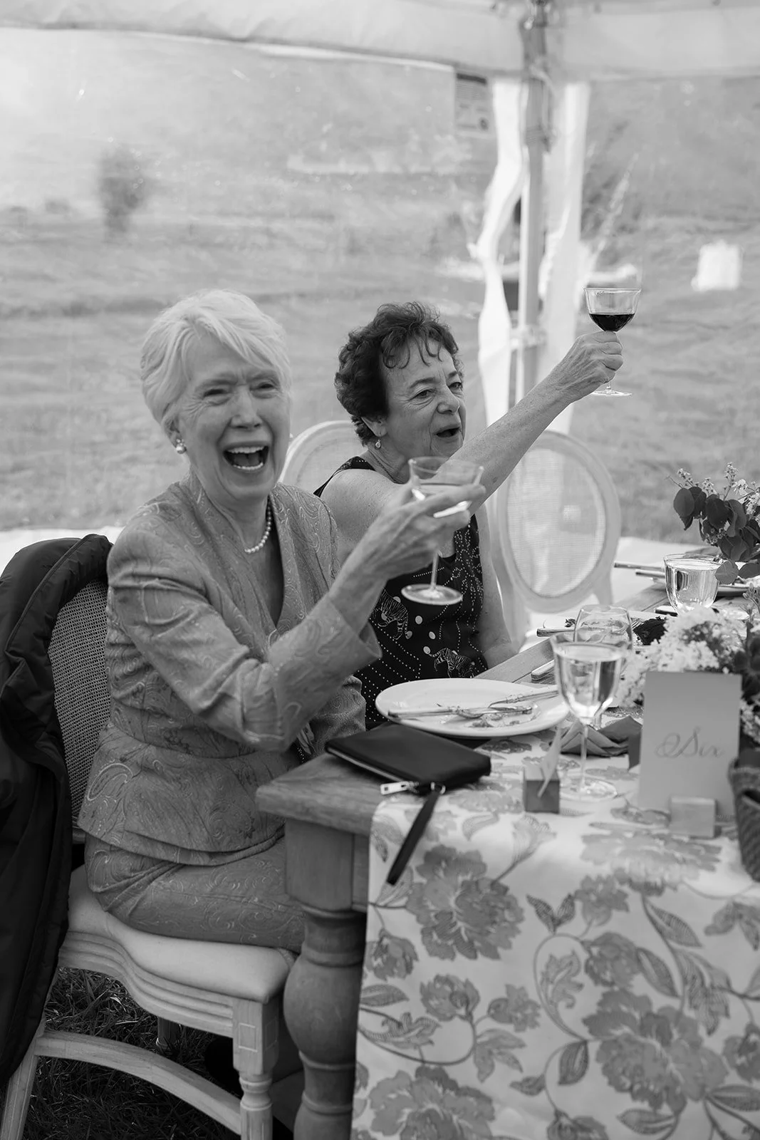 Candid natural photography of grandparents at wedding reception holding up their glasses to cheers the bride and groom in Jackson Wyoming at Snake River Ranch by Laura Powers photo 