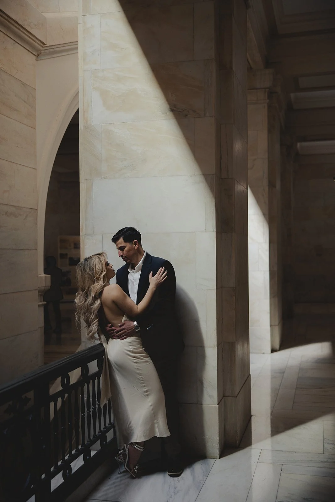 A couple embracing in a marble hallway with soft lighting.
