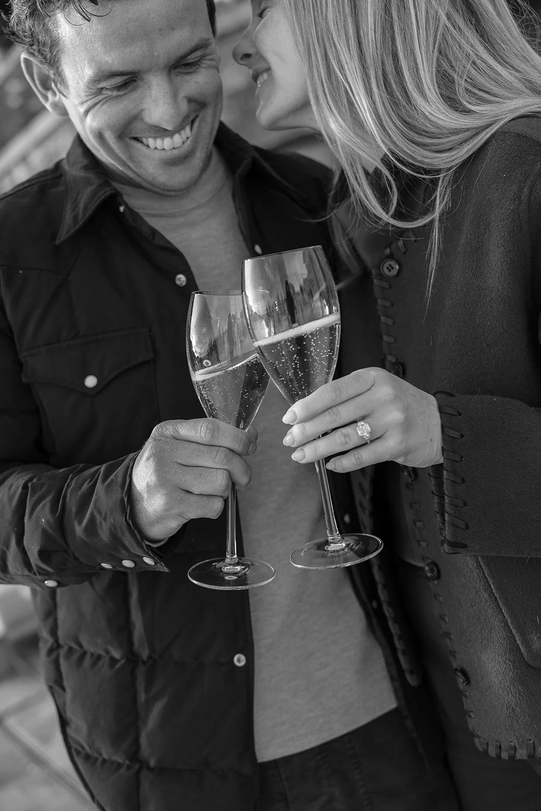 A smiling man and woman holding glasses of champagne, toasting each other, celebrating together.