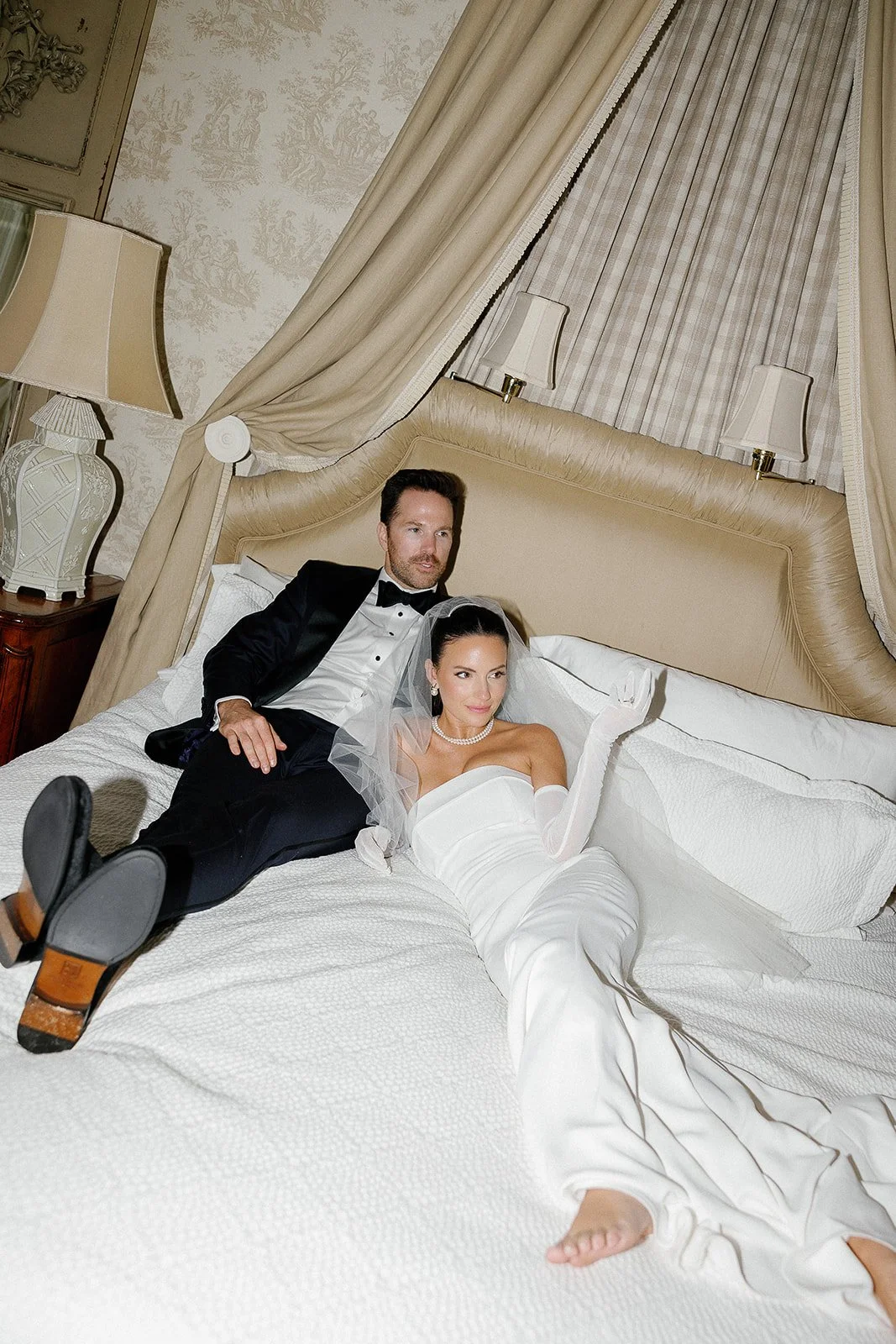 Modern high fashion bride with gloves and groom portraits in hotel bed with flash photography by Laura Powers Photo