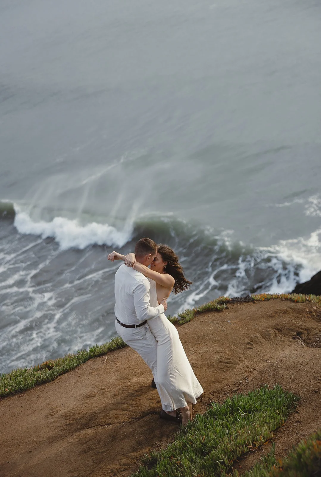 Couple embracing on a cliffside by the ocean