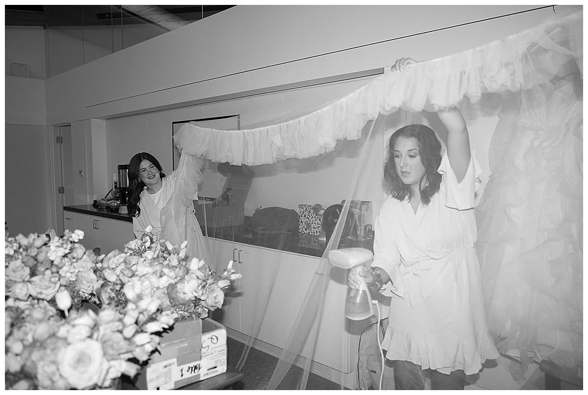 Cute Flash wedding photography of Bridesmaids steaming brides veil at Crystal Bridges Museum of Art in Bentonville, Arkansas, By Laura Powers Photo