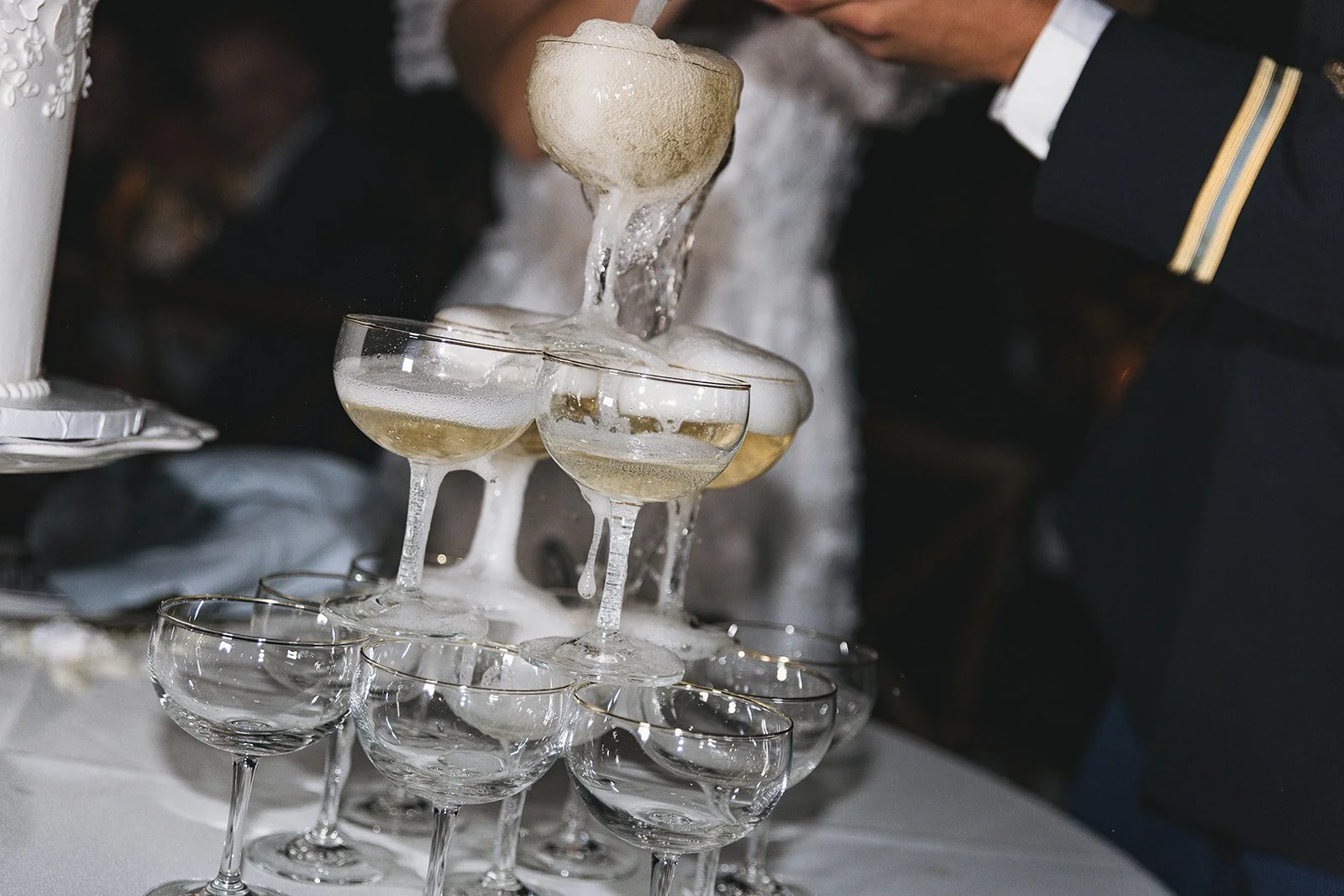 Stunning flash photography of bride and groom pouring champagne into a champagne tower by Laura Powers Photo