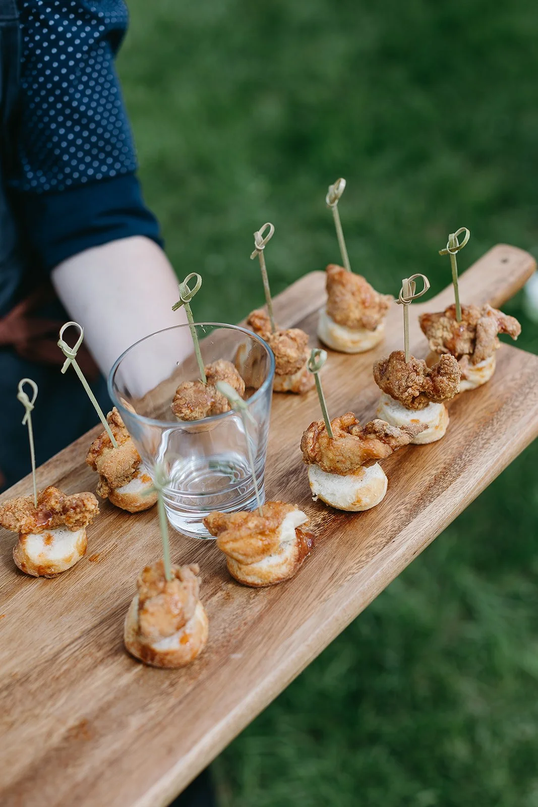 Appetizers on skewers with fried chicken pieces and bread on a wooden board.