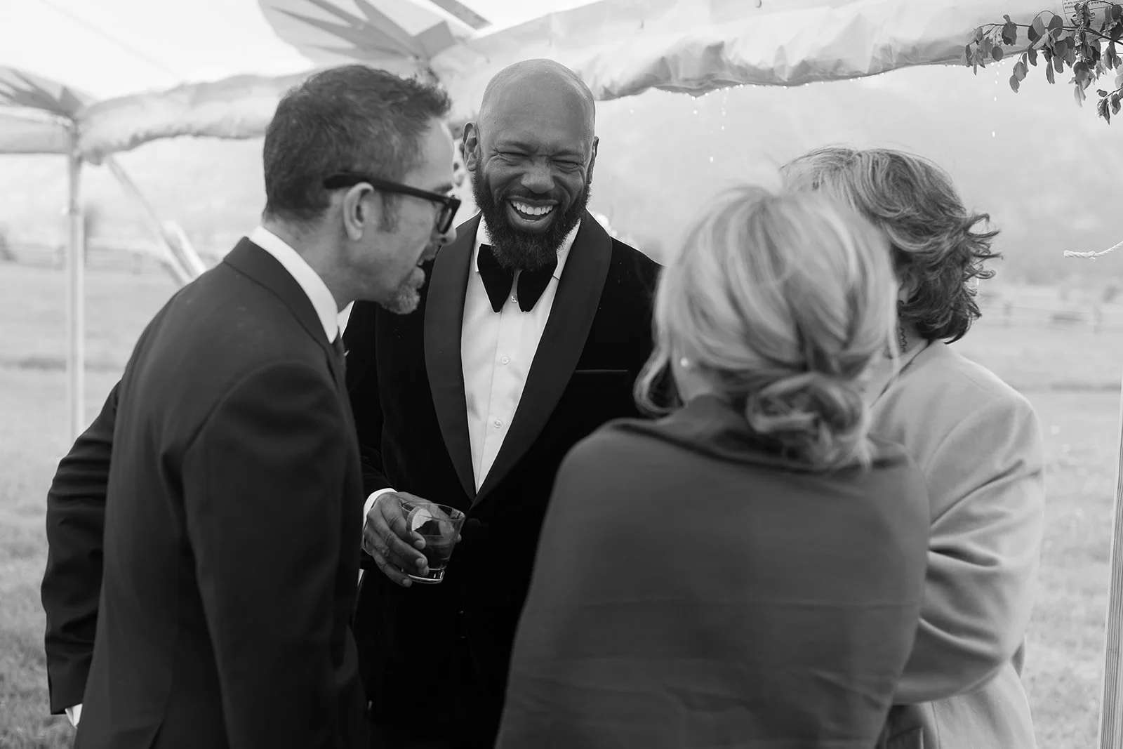 Group of people in formal attire laughing and talking outdoors at an event.