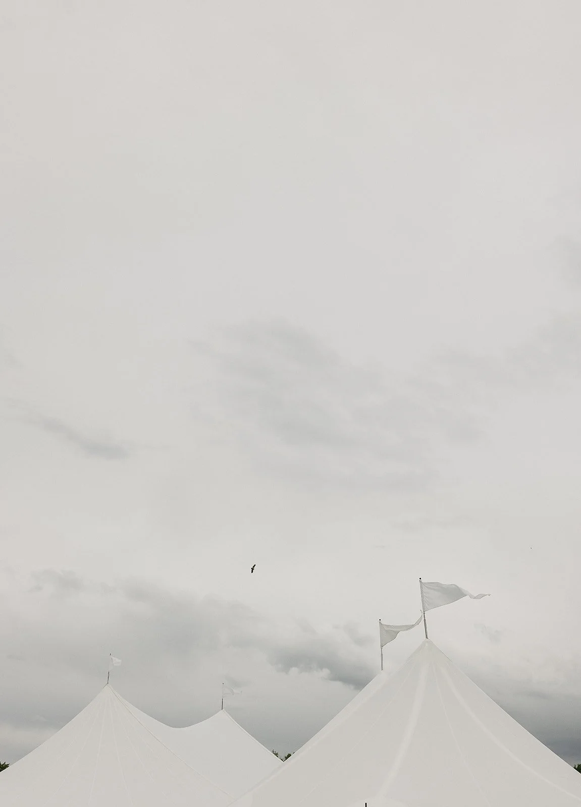 White tents with flags against a cloudy sky.